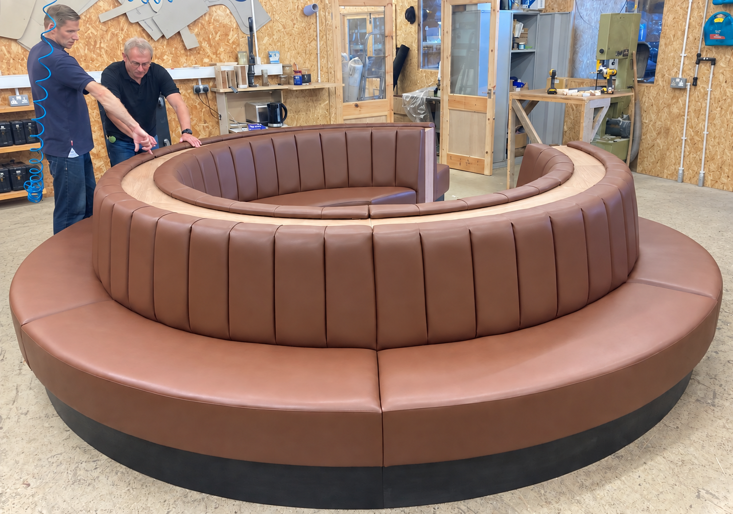 MHF team beside a circular upholstered banquette at the workshop